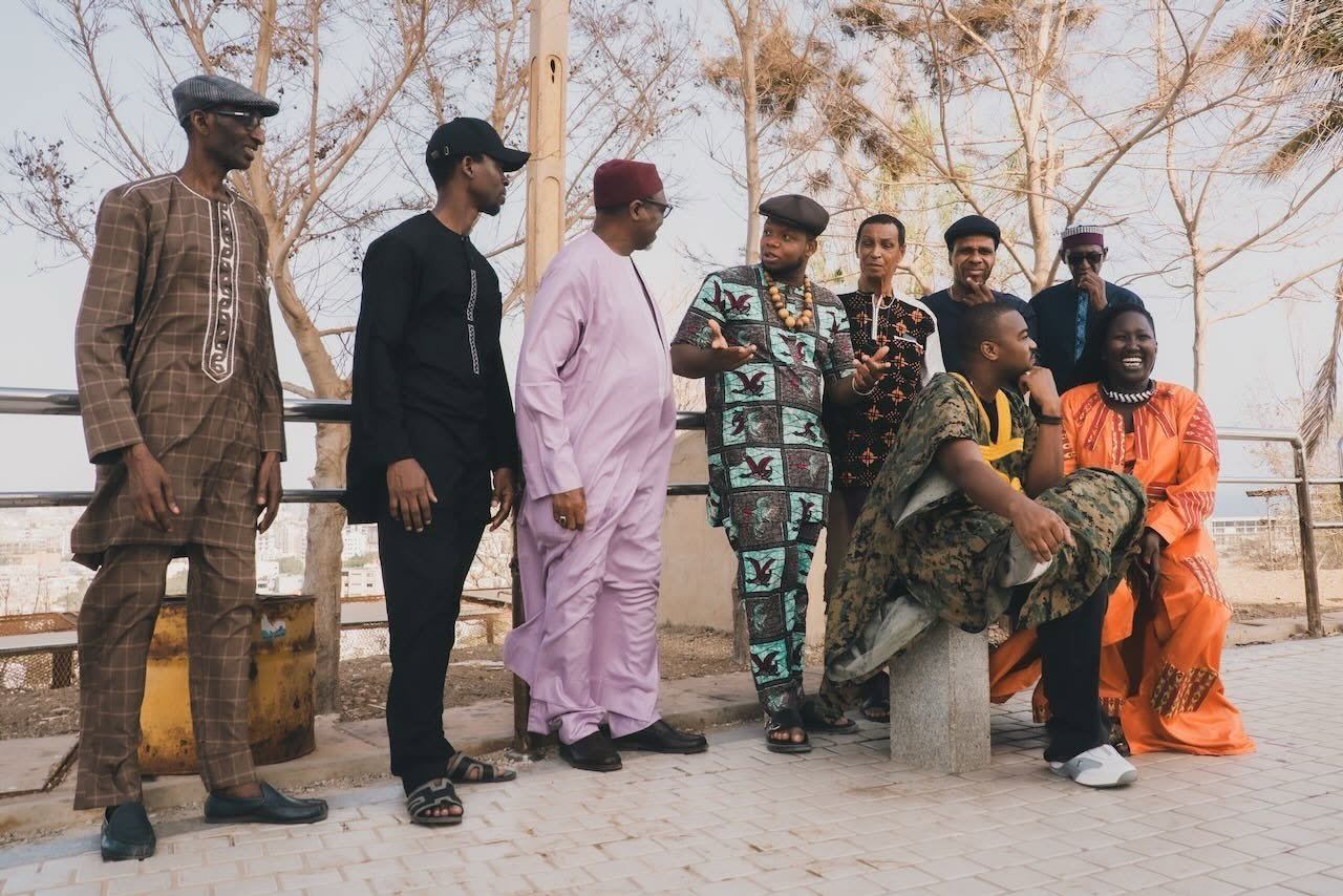 The nine members of Orchestra Baobab in traditional and modern dress on a terrace in Dakar
